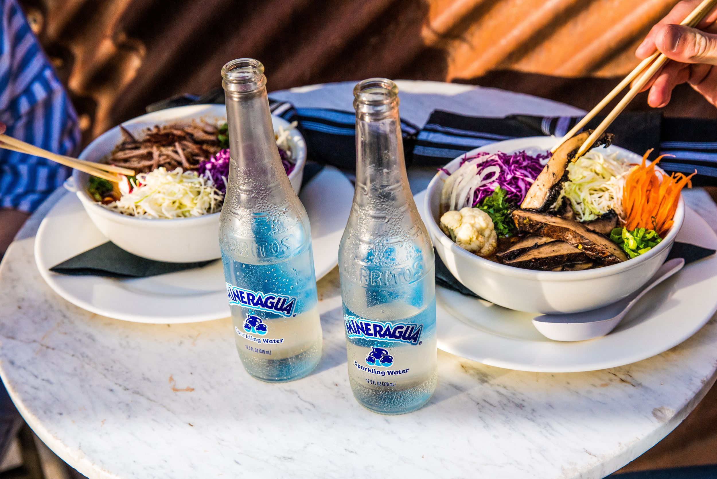 Two Mineragua waters on a table next to colorful and fresh salads