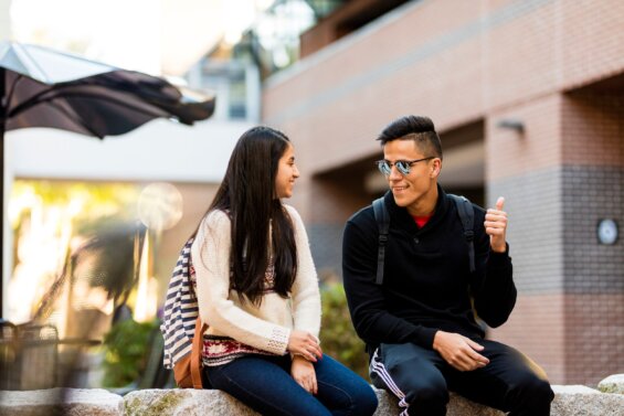 Young man and woman sit on a campus plaza and have a discussion