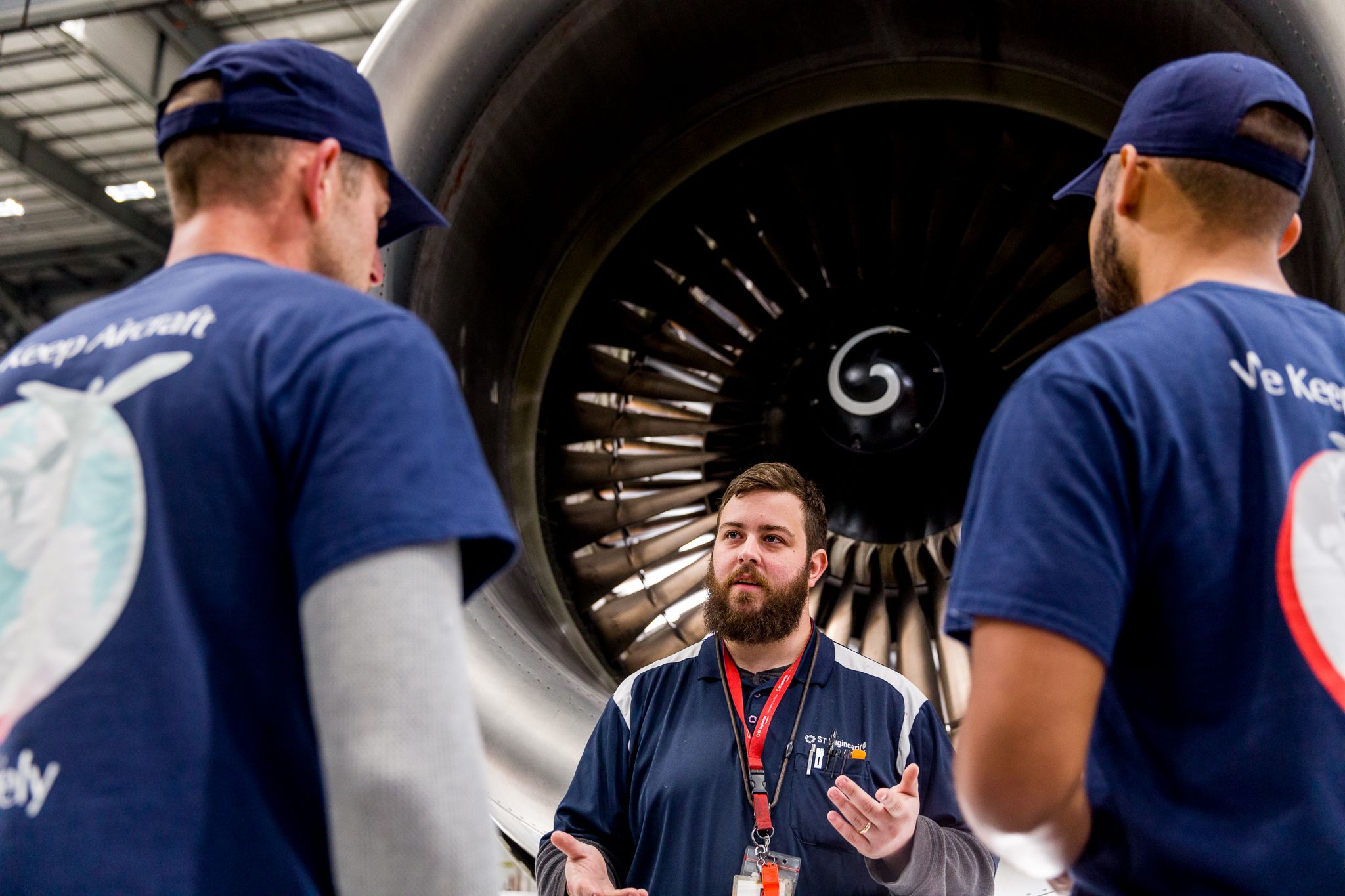 Man teaches two employees next to airplane