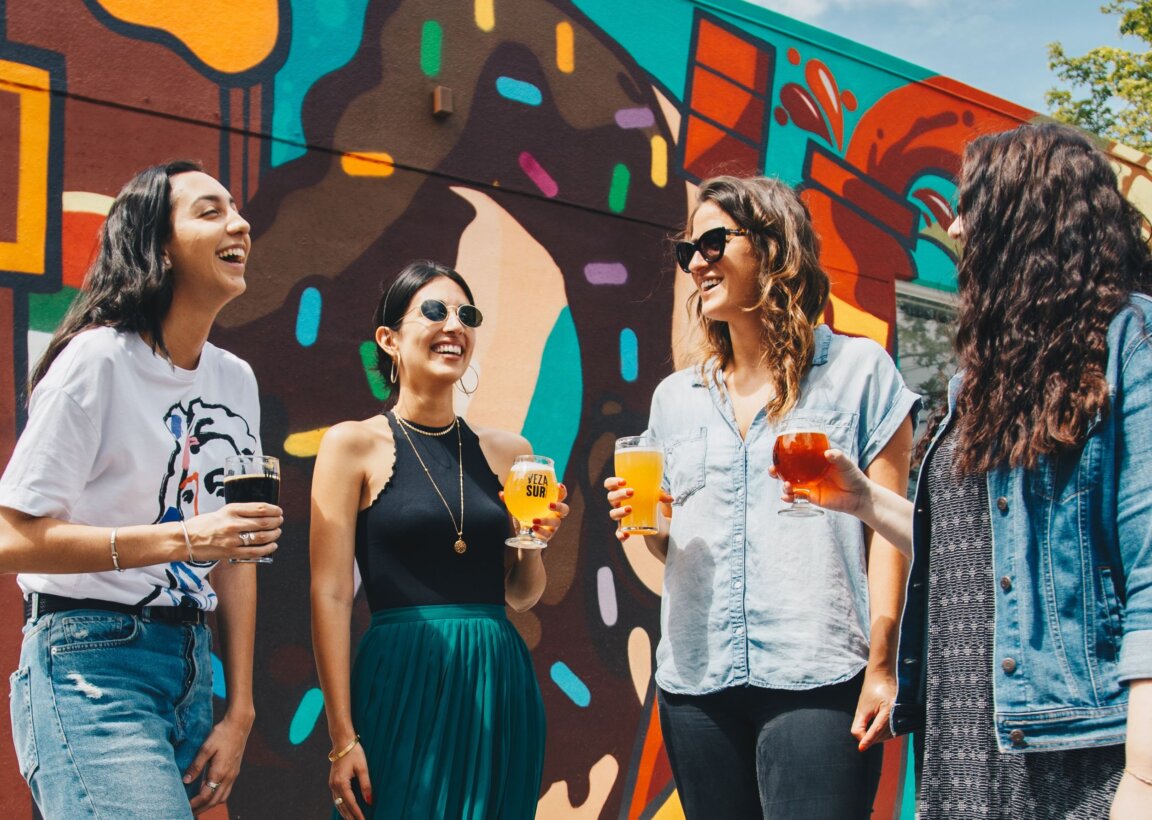 Group of four women chat in front of colorful wall